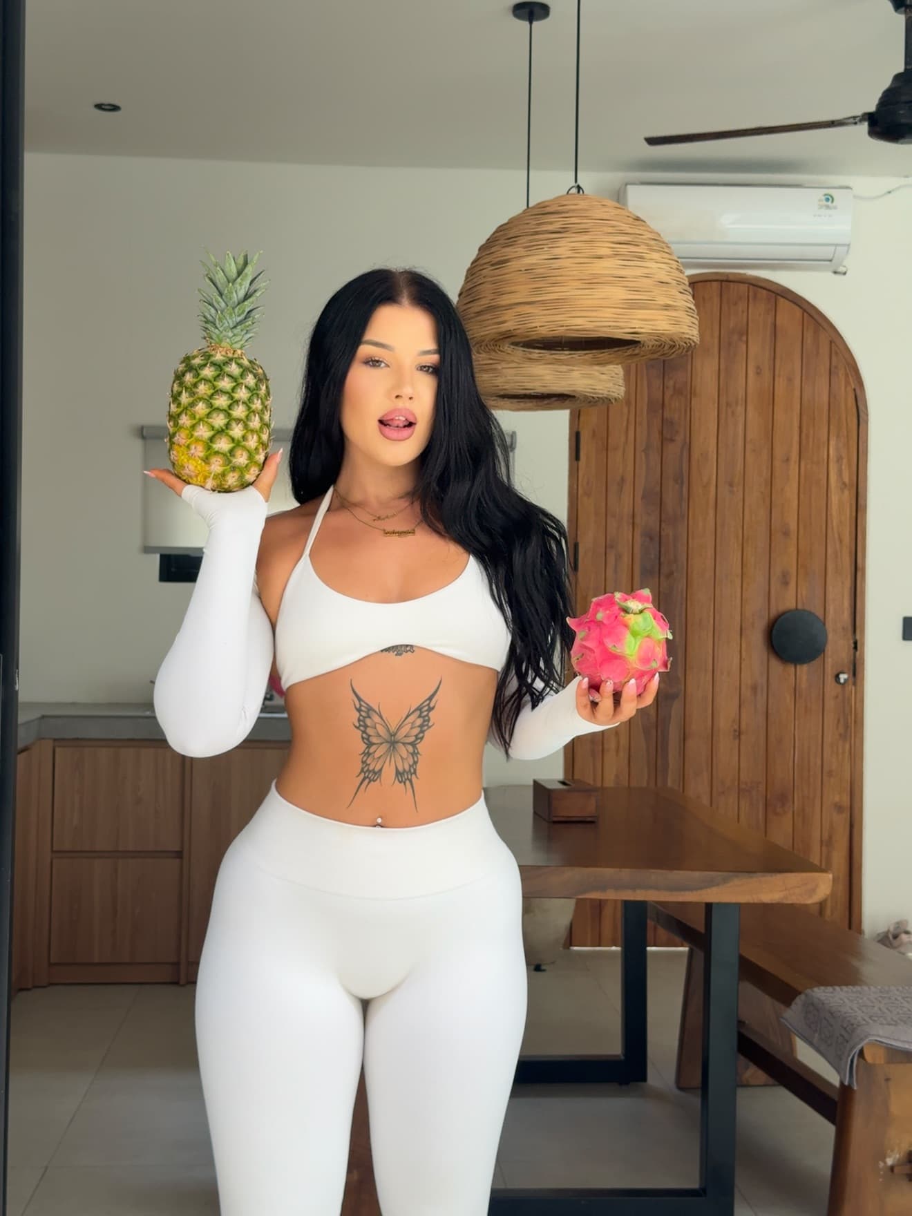 Amber, online coach and nutrition specialist, holding a pineapple and a dragon fruit
